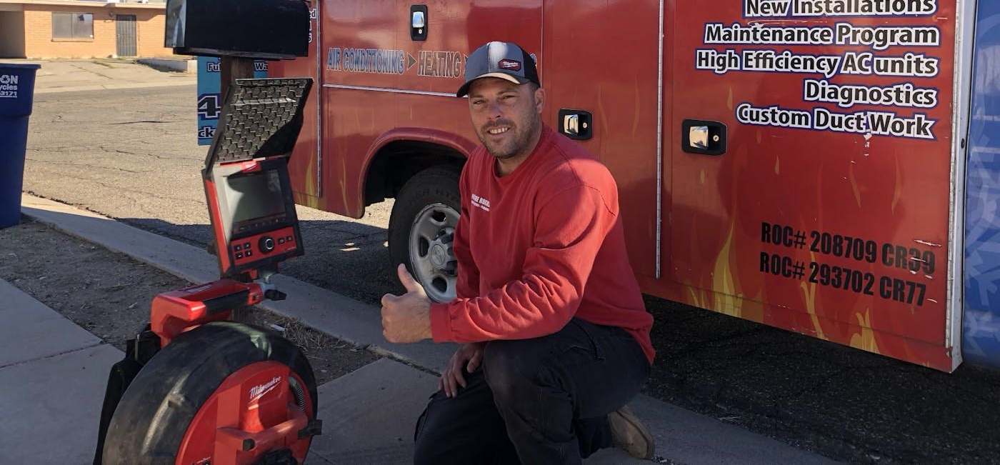 Picture Rocks technician kneeling beside a branded HVAC service truck